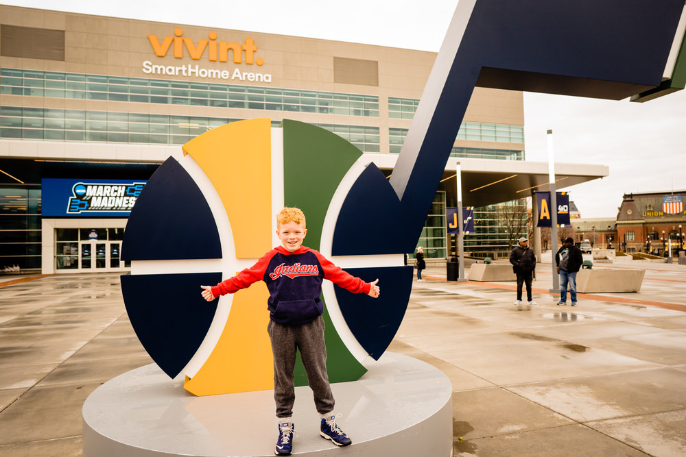 Planning your epic Utah family vacation. Young boy standing outside the Vivint stadium where the Utah Jazz play