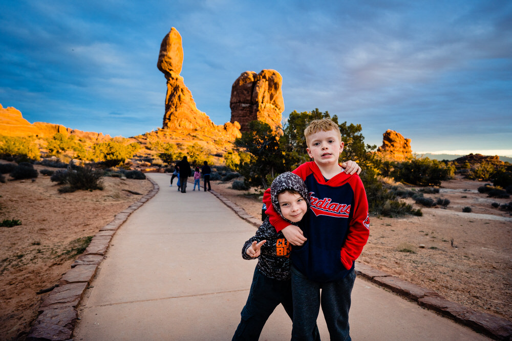 Planning your epic Utah family vacation. Two brothers play on the trails of Arches National Park.