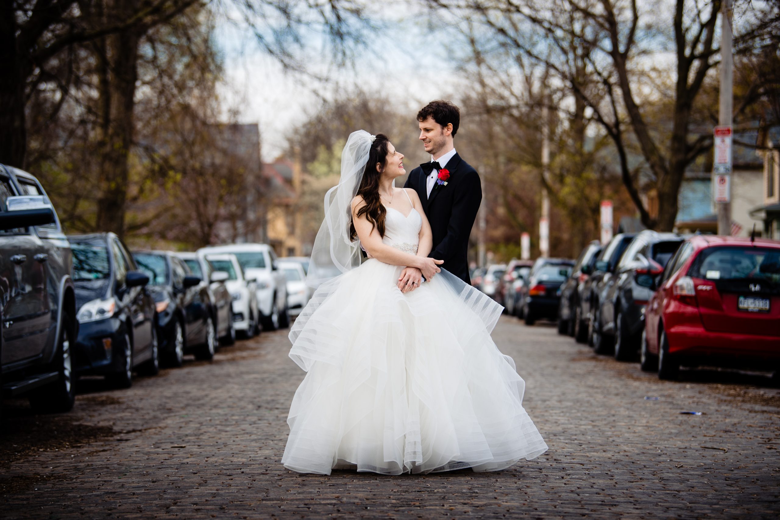 A bride and groom standing in the street on their wedding day